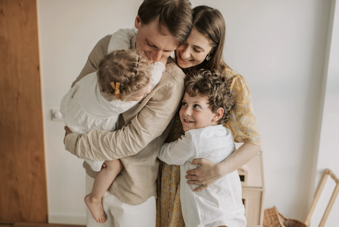 A family of four embracing and smiling together